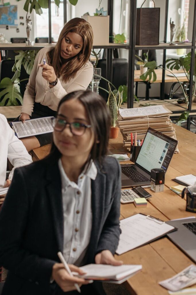 The Art of Drawing Readers In: Your attractive post title goes here Asian and Black women collaborating in a vibrant office space, promoting teamwork.