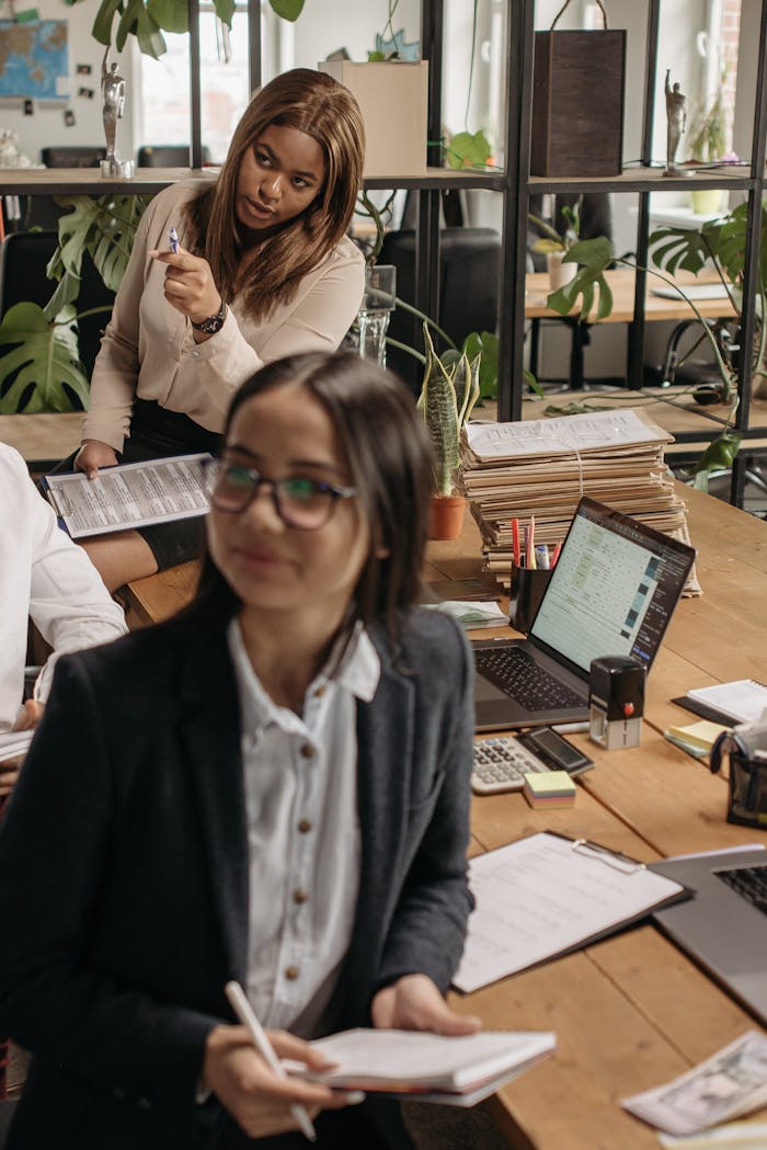 The Art of Drawing Readers In: Your attractive post title goes here Asian and Black women collaborating in a vibrant office space, promoting teamwork.